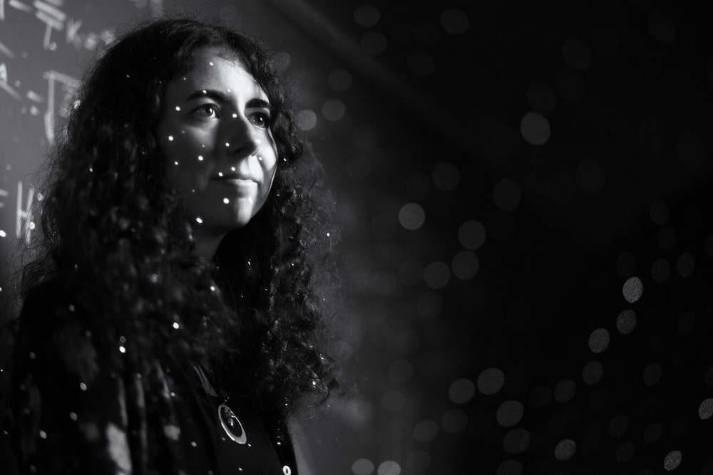 Marshall University physics alumna Ellie White is illuminated by projected points of light during a portrait highlighting her interest in astronomy and the search for extraterrestrial intelligence.