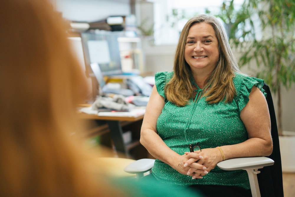 Leah Tolliver, assistant dean of wellness in Marshall University's Division of Student Affairs, smiles while meeting with a student in her office.